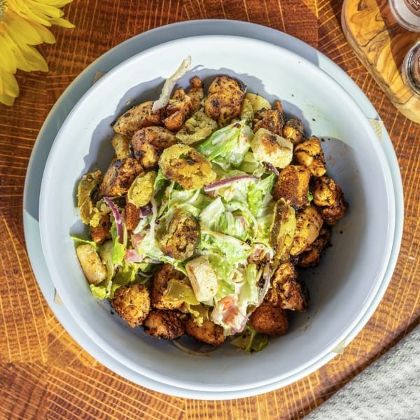 Overhead view of a seafood salad with grilled shrimp, lettuce, croutons, and fried green tomatoes.