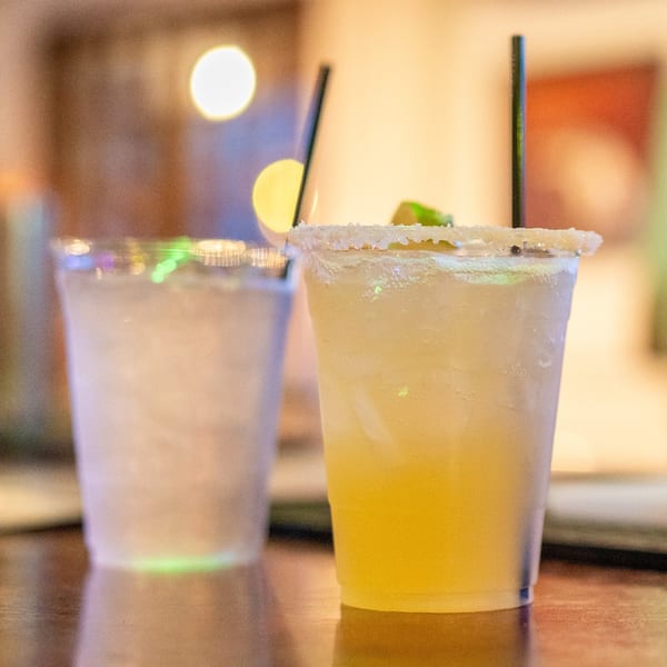 A salt-rimmed margarita with a lime wedge and a water cup on a bar at OSO at Bear Point Harbor.